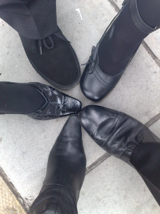 four pairs of black shoes standing in the middle of a circle