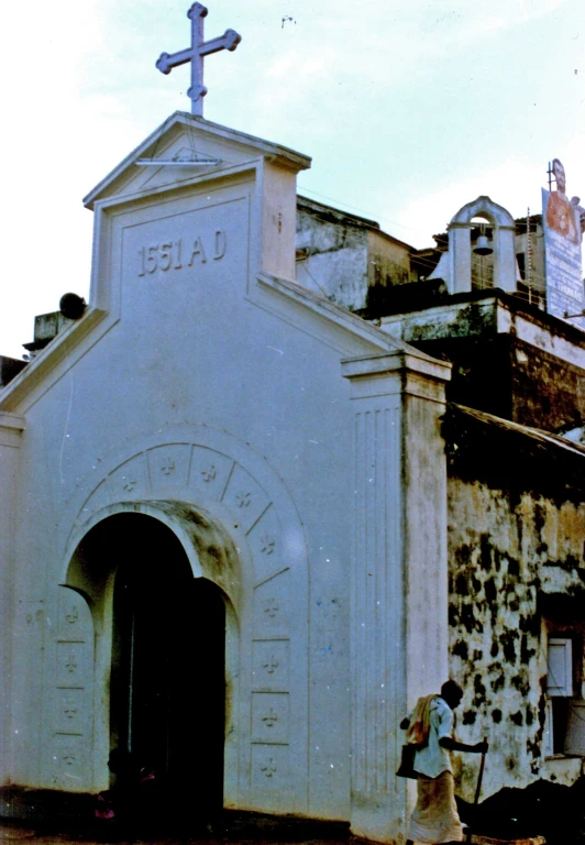 people and bicycles stand in front of an old church