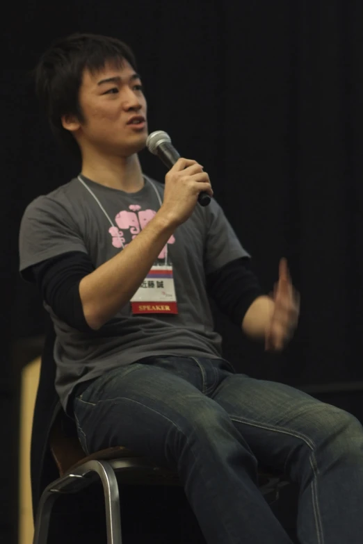 a man sitting in front of a microphone on top of a chair