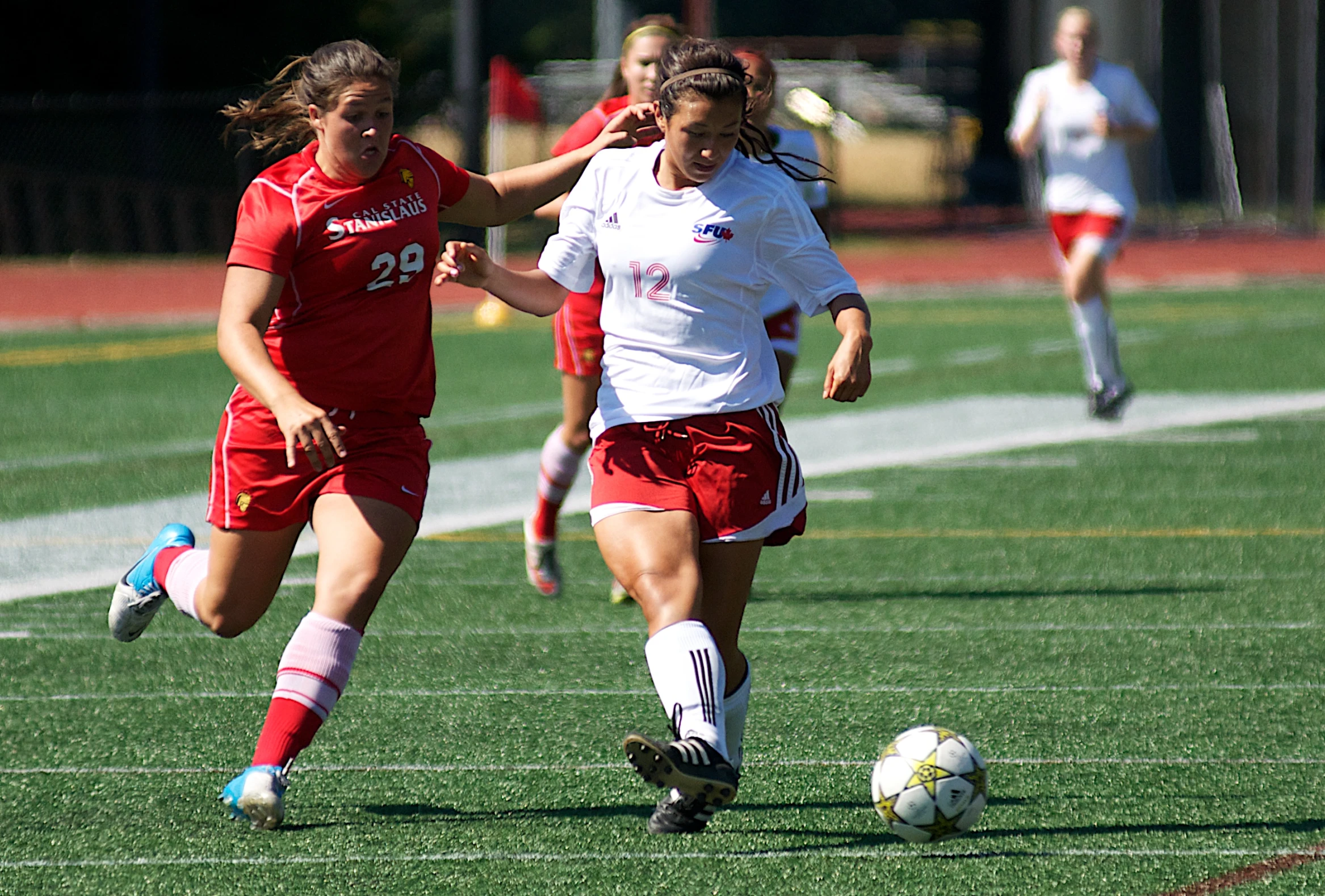 girls in uniform running after a soccer ball