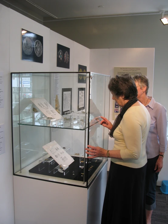 a woman holding a display case filled with lots of items