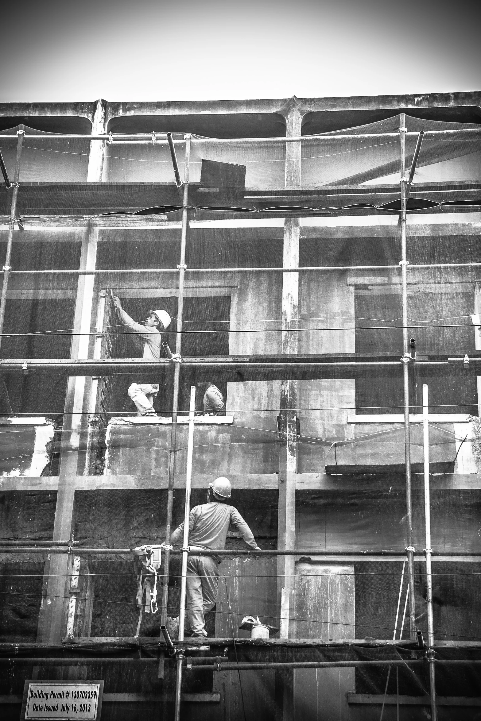 two workers stand at a window sill as another works on the side