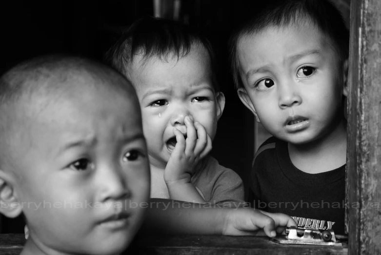 two little boys are looking out of a window