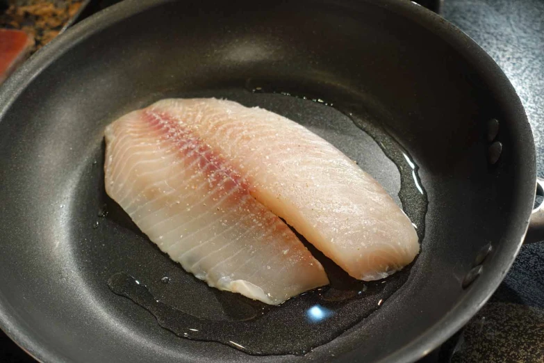 a raw fish fillet is in a wok