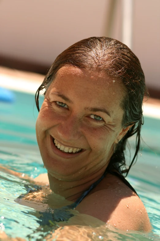 smiling woman in water pool with head tilted toward camera