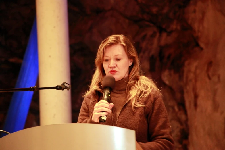 a woman in a brown shirt holding a microphone