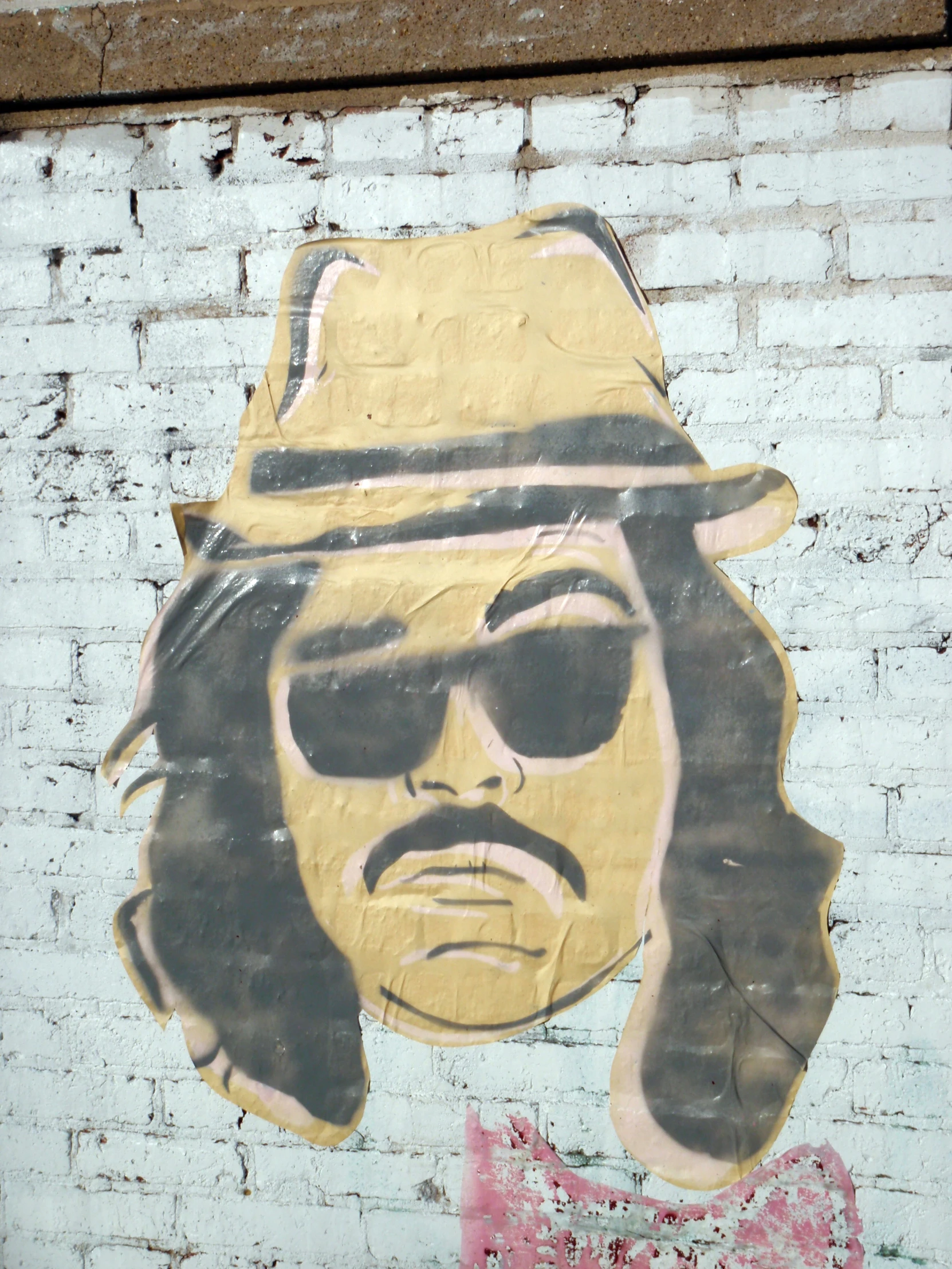 the picture of an old fashioned bob marley wearing sunglasses and hat on a white brick wall