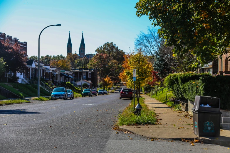 a street with trees and cars on it near some buildings