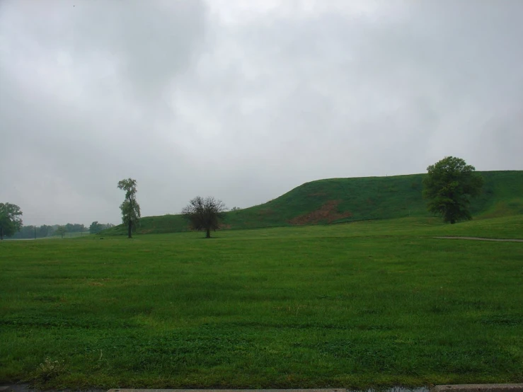 an empty field with a green hillside on the side