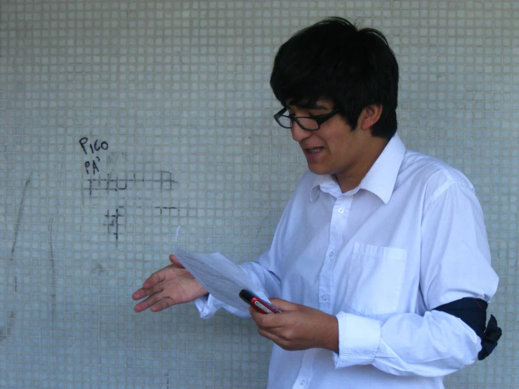 a boy wearing glasses writing on a piece of paper