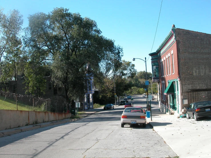 a street with cars parked on both sides and many trees around