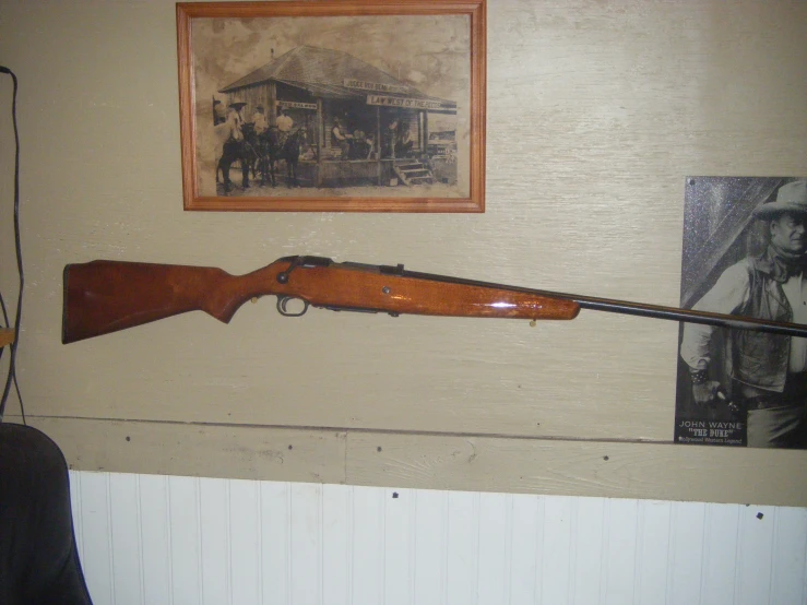 a rifle mounted on the wall next to a picture