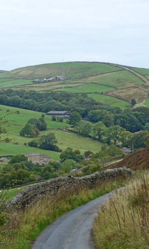 a road curves through the countryside with hills and buildings