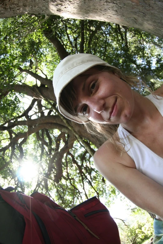 a smiling woman in a sun hat holds her hands against her waist