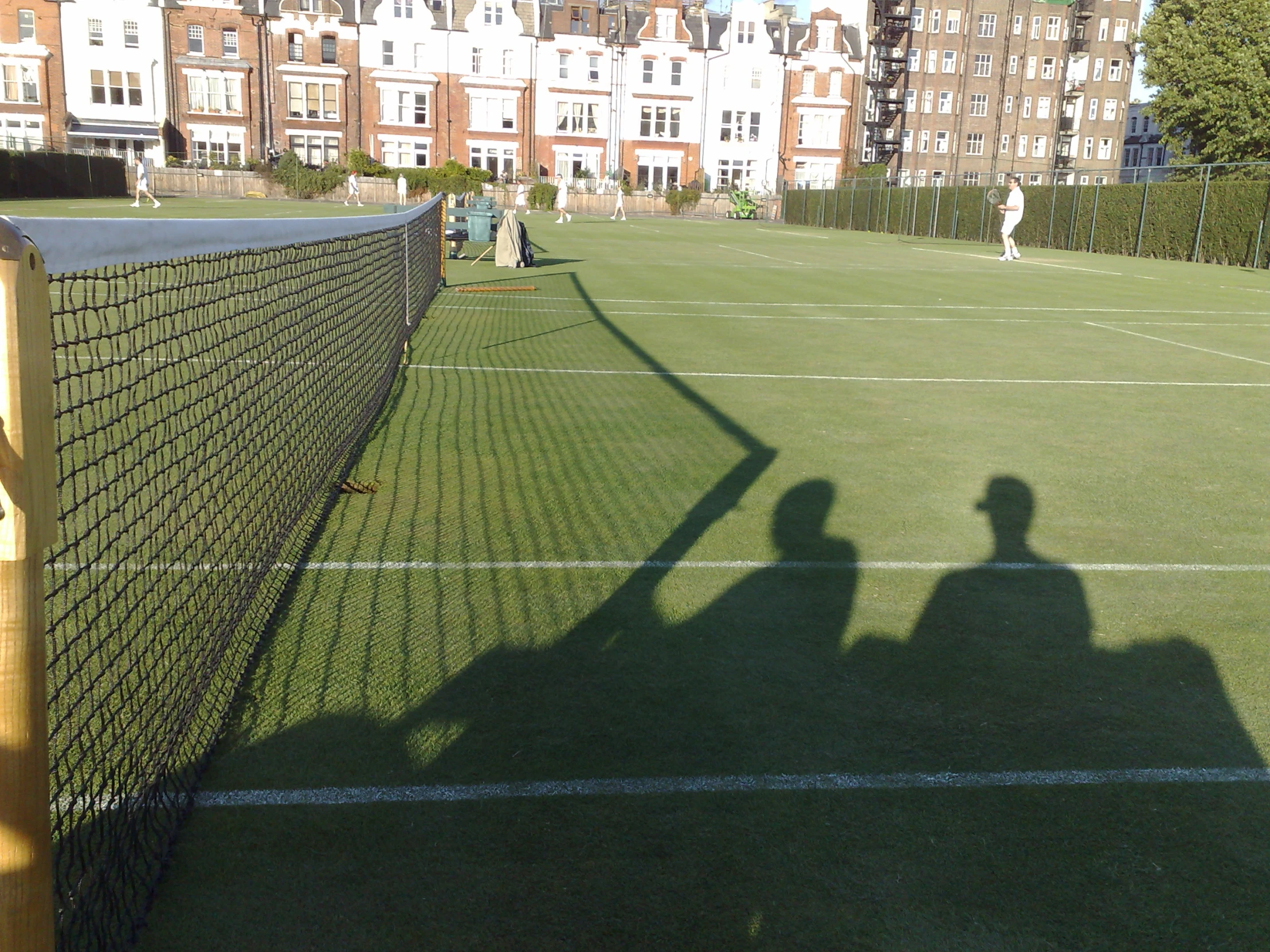 a person on a tennis court in shadow