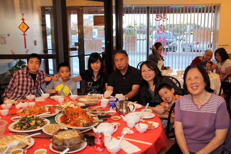 a group of people smile together while seated around a table full of food