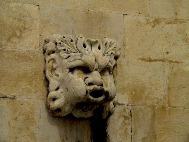 a stone face hanging on a wall by bricks