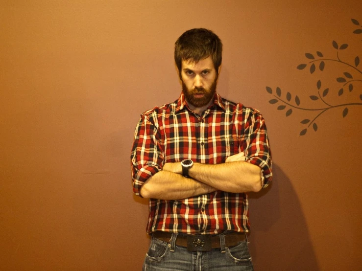 a man wearing plaid shirt and jeans with arms crossed