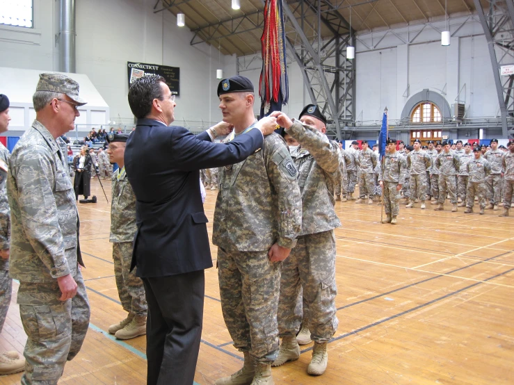 a man pinning a medal to some soldiers