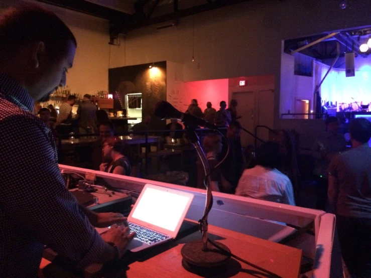 a man is typing on a laptop in a bar