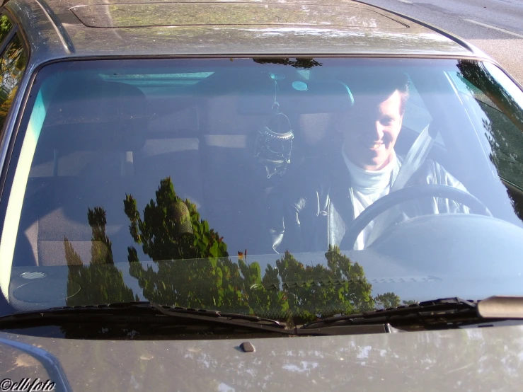 a man sitting in a car driving past trees