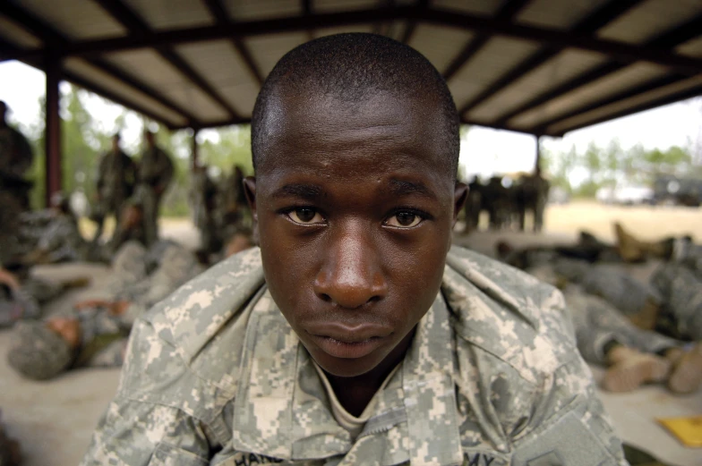 young army personnel and others stand under a shelter