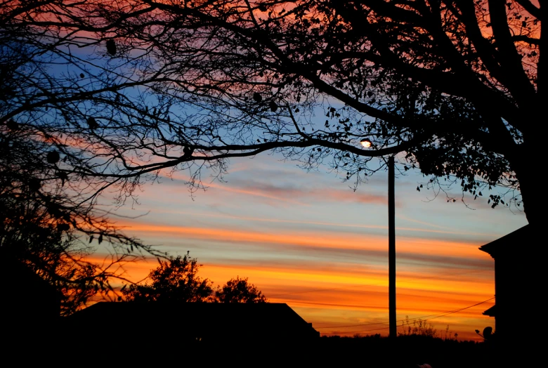 a sunset with trees and a street lamp