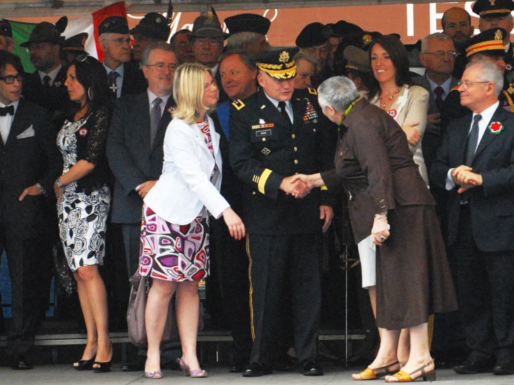 two people shaking hands while other people watch