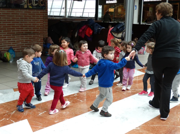 many children and an adult are dancing on the floor