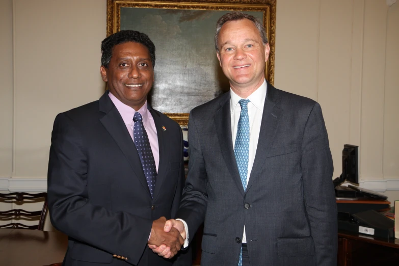 two men in suits shaking hands with one another