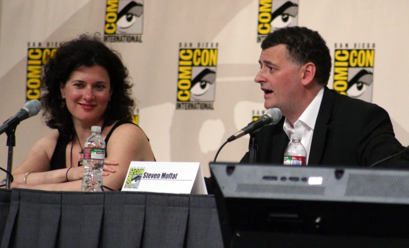 a man and woman in front of microphones at a comic convention