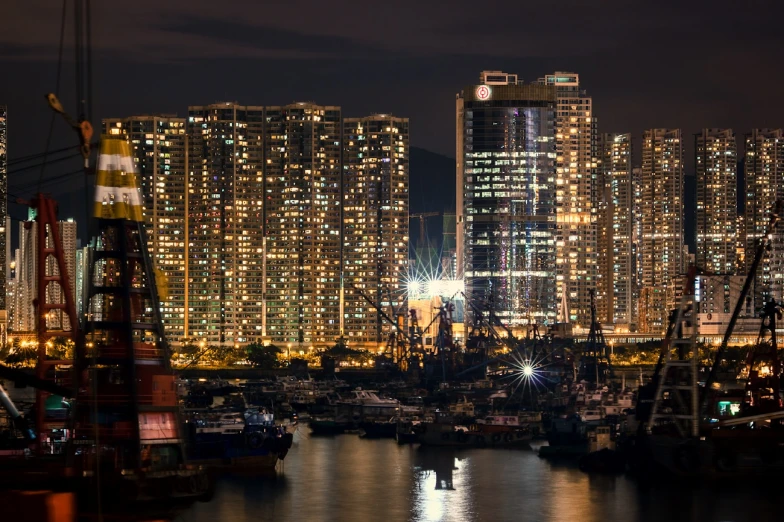 some boats are in the water and lights shine on some buildings