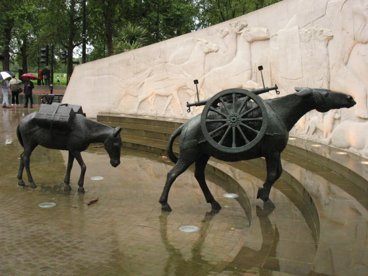 two statues of horses are displayed near a wall