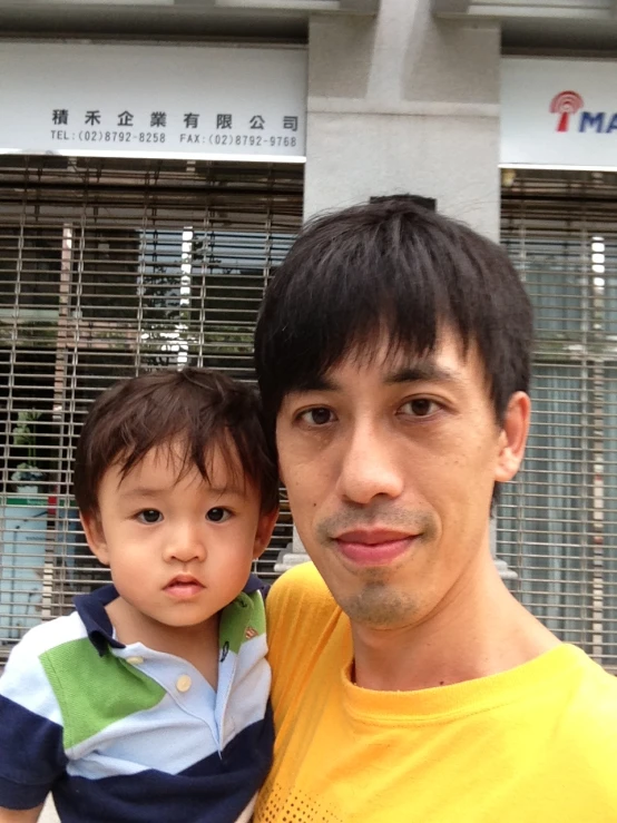 a man with black hair holding onto a small child