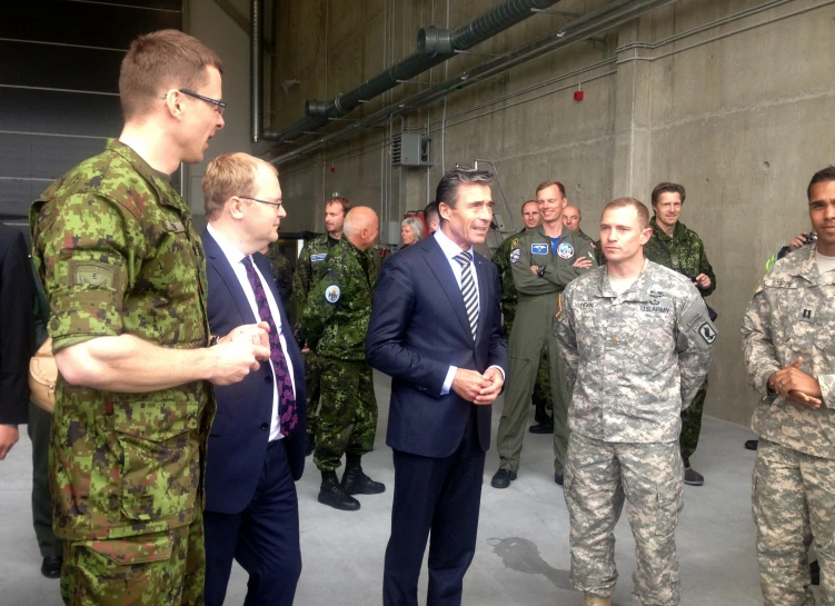 two men talking in front of men in uniform