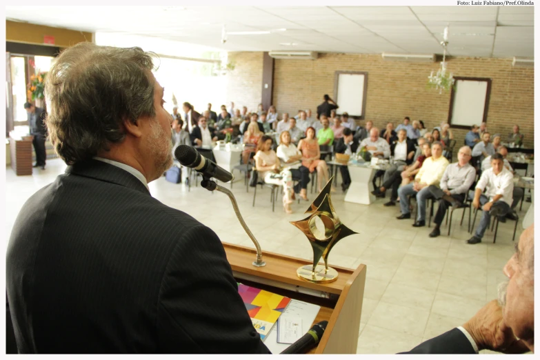 a man is speaking into the microphone as an audience watches