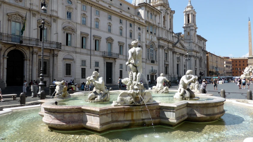 a large building with a fountain and statues in front