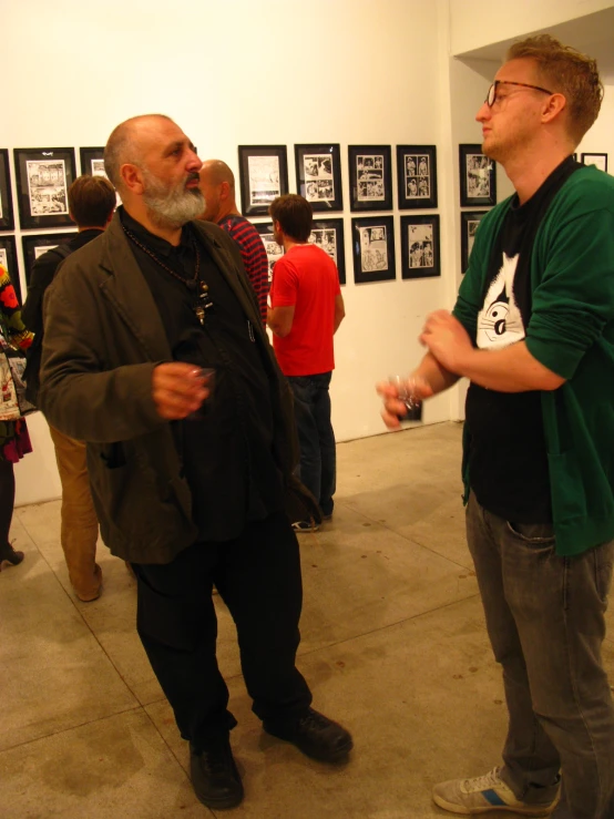 two men standing next to each other looking at pictures