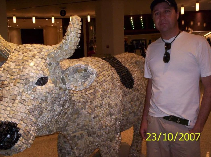 a man standing next to an elephant made out of many little lego bricks