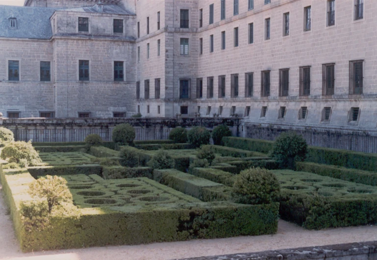 a large courtyard has a maze of hedges in front
