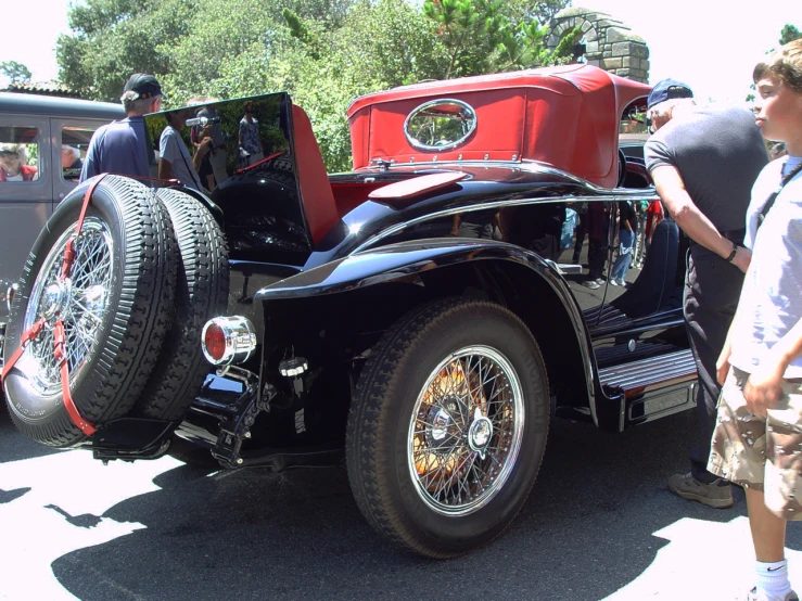 people looking at antique cars with other vehicles in the background