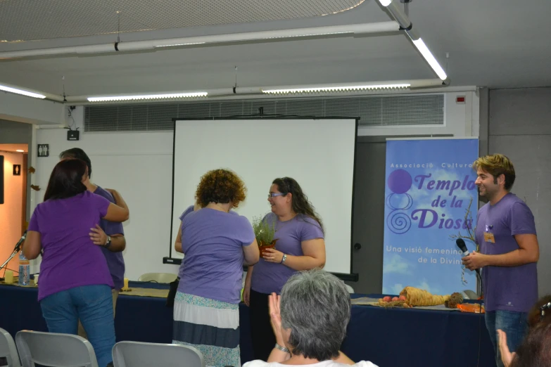 a group of people standing around talking in front of a projector screen