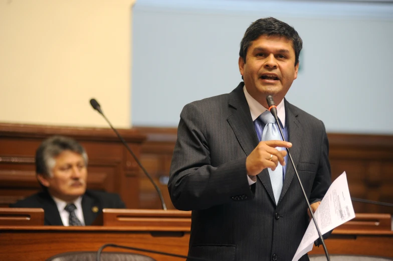 a man in suit speaking into microphone at a convention