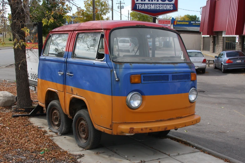 an orange and blue van parked on a sidewalk