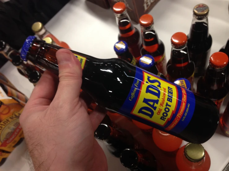 a bottle of beer is being held above a pile of soda bottles