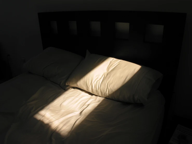 a bed is lit by sunlight through the window