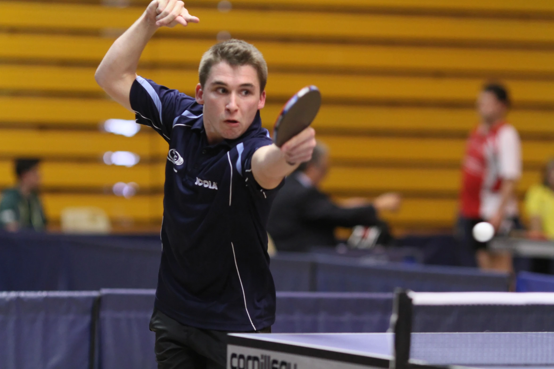 a male in black shirt playing ping pong