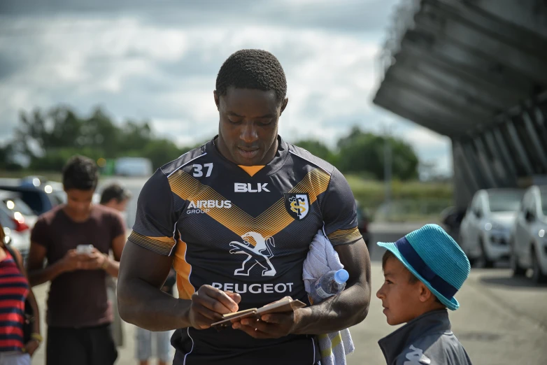 a young man holds a baby while people stand in the street