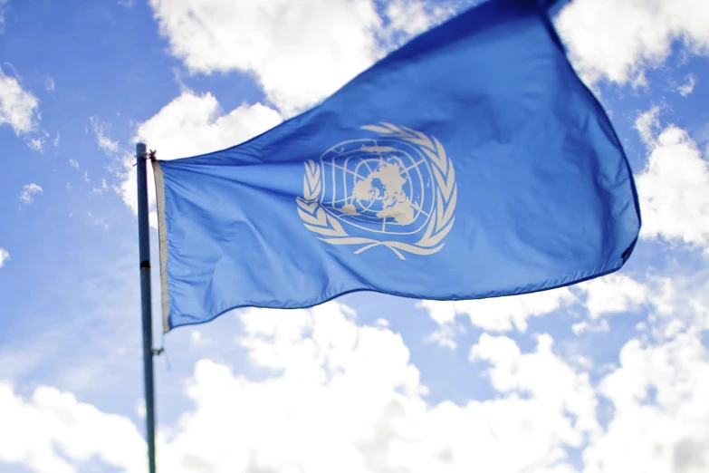 the united nations flag waving against a blue sky
