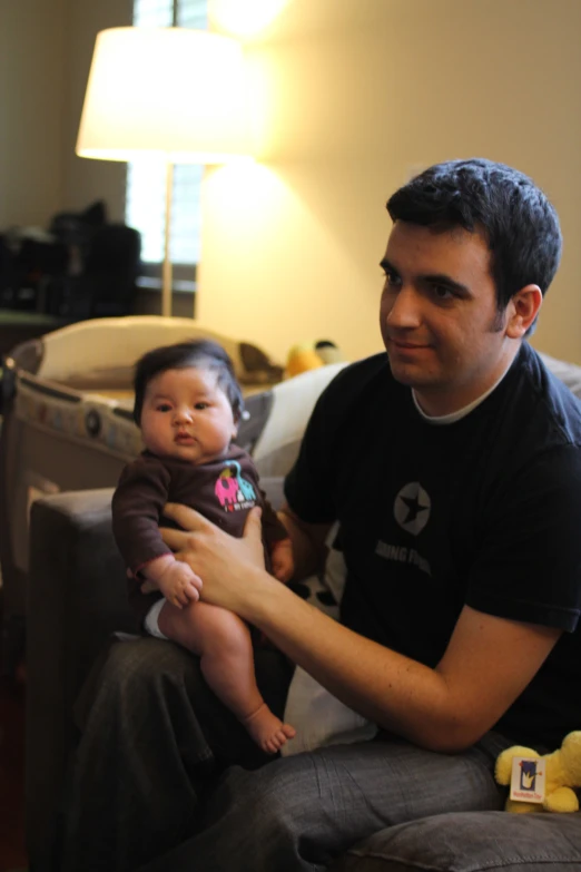 a man sits on a couch holding a small child